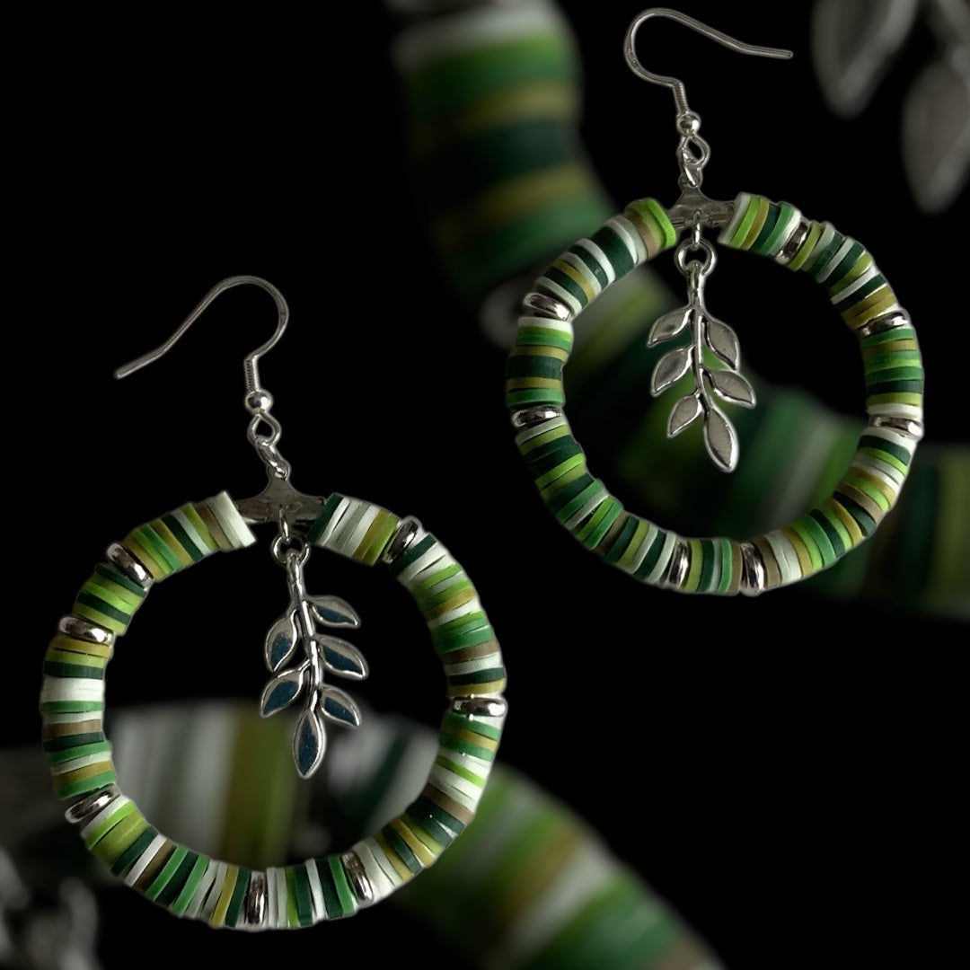 Handmade hoop earrings with polymer clay beads in soft green, nude, and natural tones, accented with silver spacer beads, earthy and lightweight jewellery on a dark background